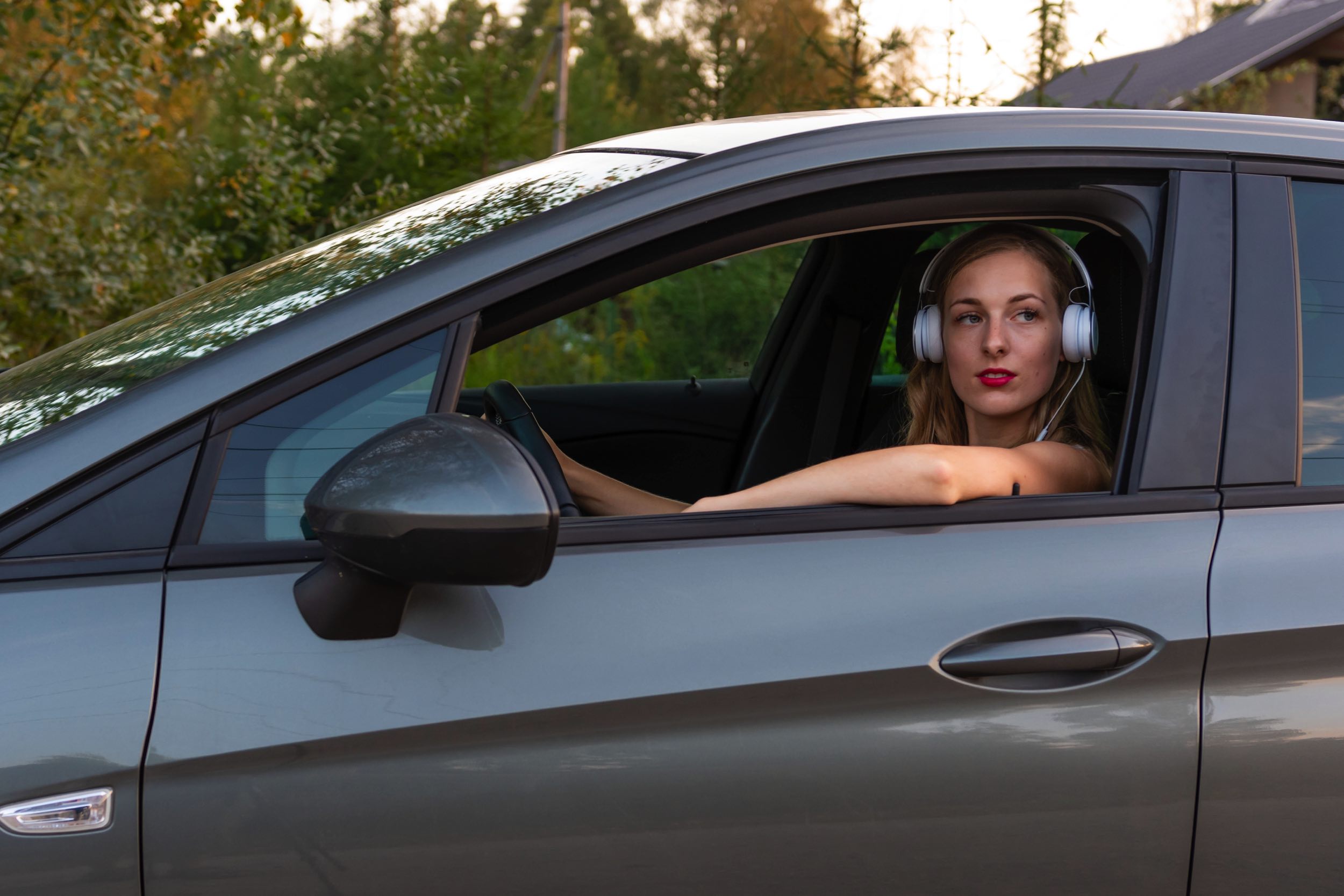 Kobieta prowadzi auto w słuchawkach